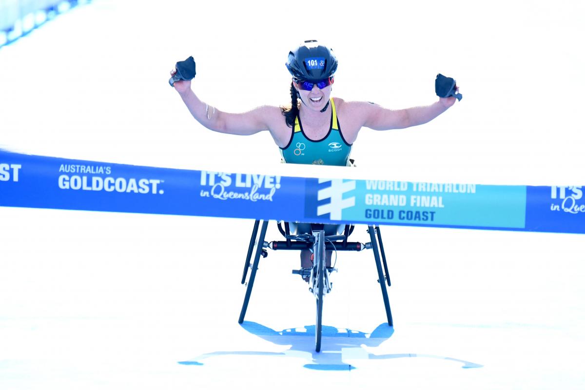 Emily Tapp - Australia - triathlon Australia woman in wheelchair raises arms before crossing finish line