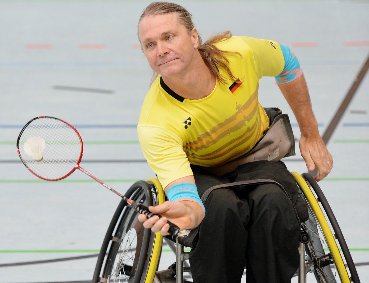 male Para badminton player Thomas Wandschneider reaches down to hit a forehand  