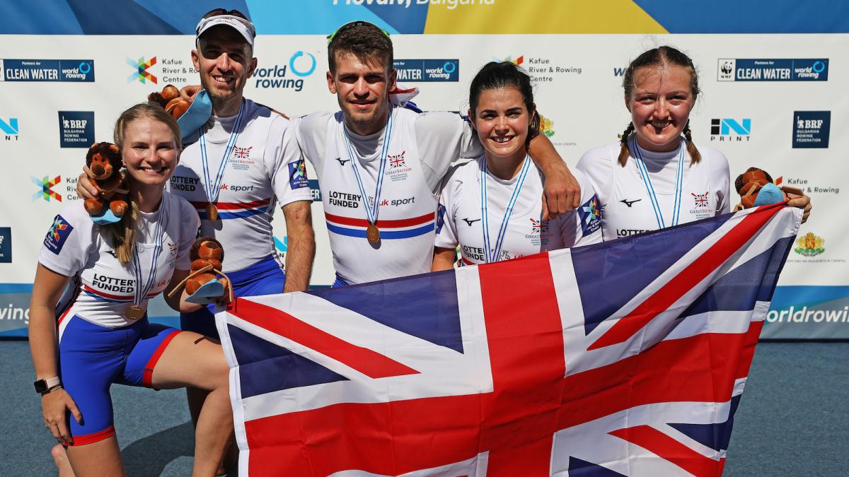 five Para rowers with Ellen Buttrick on the right holding up a Great Britain flag