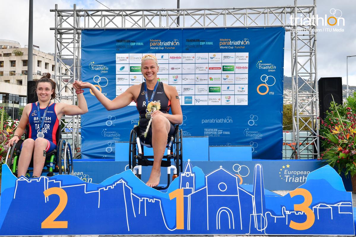 Christiane Reppe - Funchal 2018 female Para triathlete Christiane Reppe holds the hand of another female athlete on the podium