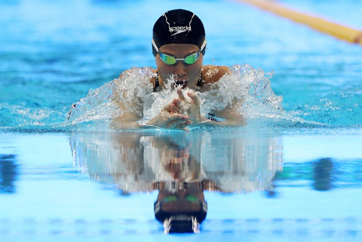 female Para swimmer Amilova Fatimakhon takes a breath during a breaststroke 