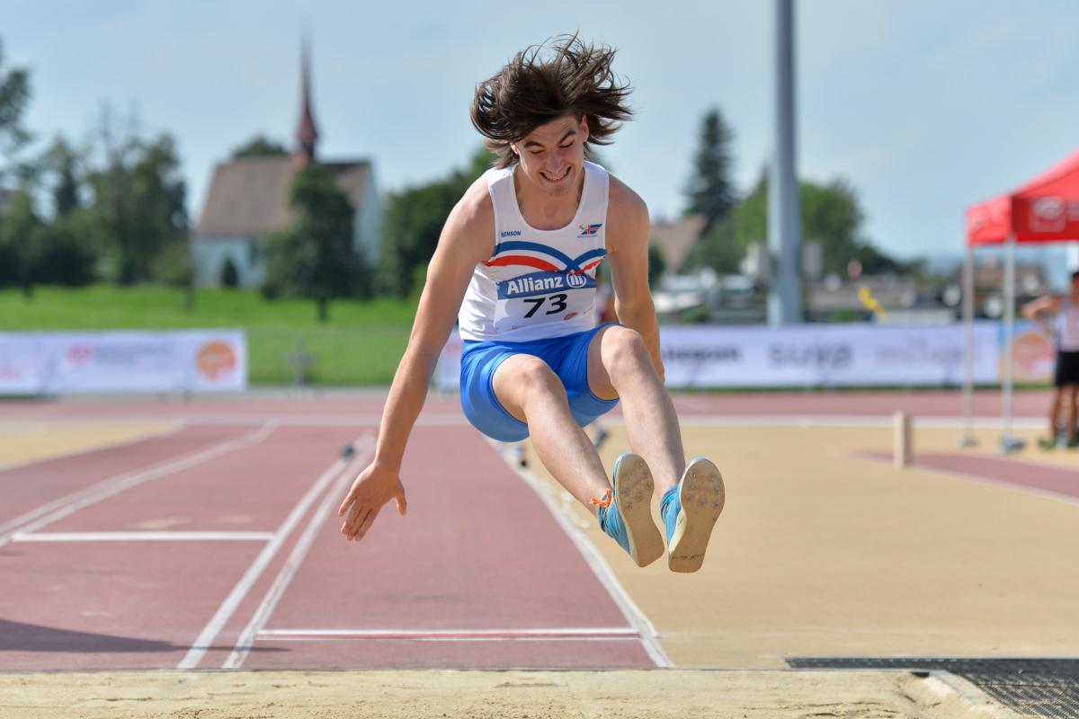 Youth athletics a male Para athlete jumps into a long jump sandpit