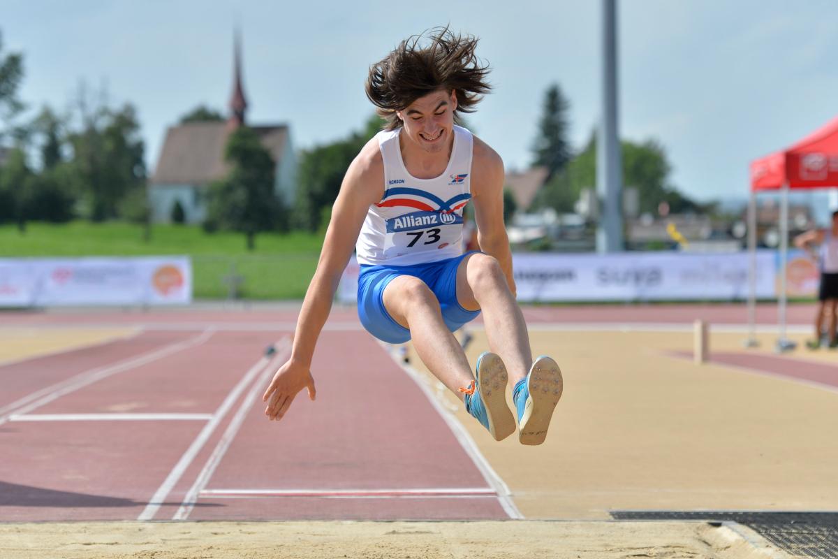 a male Para athlete jumps into a long jump sandpit