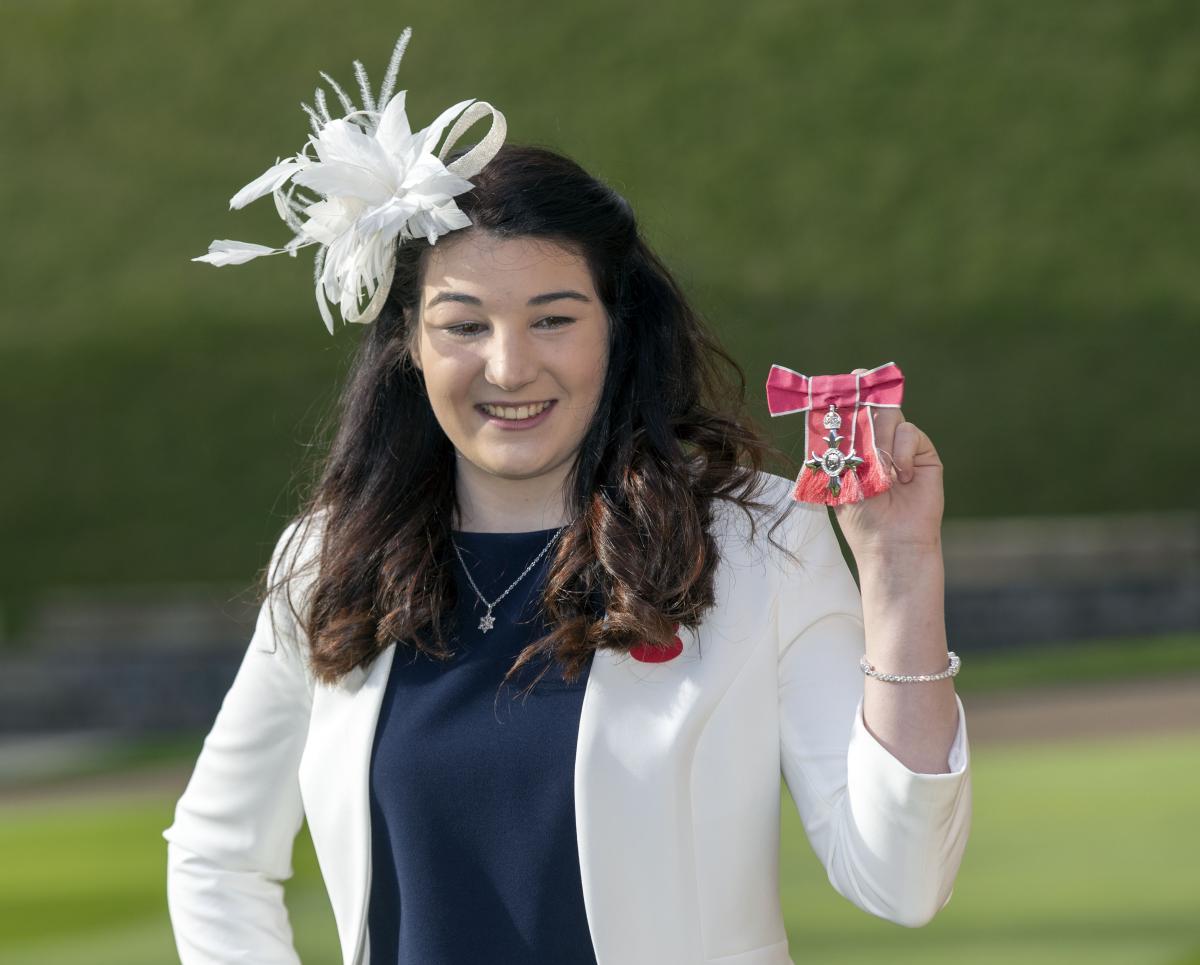 Female Para alpine skier Menna Fitzpatrick holding up her MBE medal