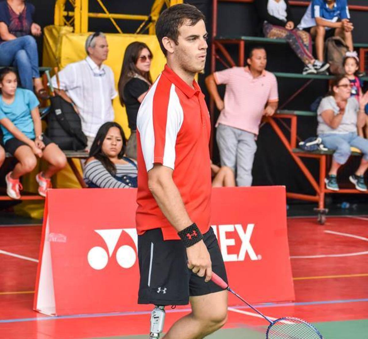 Peruvian male badminton player with prosthetic leg stands holding a racket 