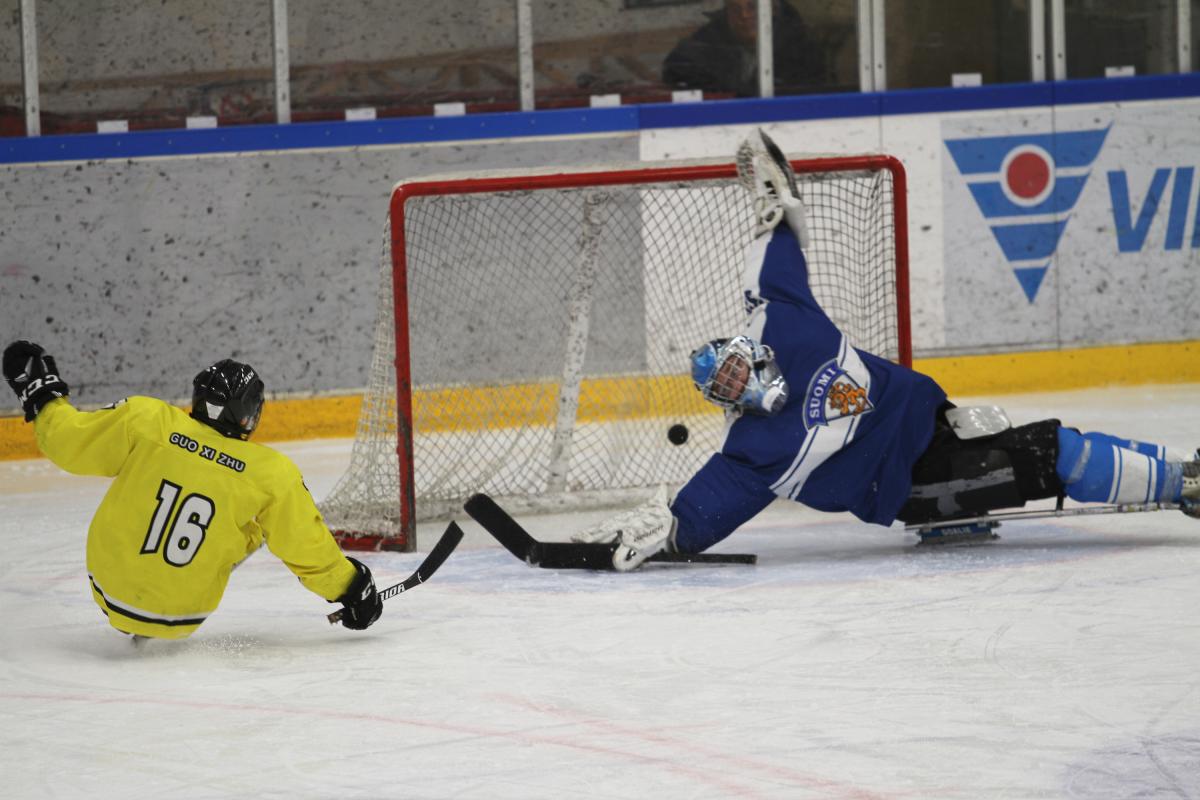Guo Xi Zhu of China - Timo Karko of Finland - C-Pool World Championships Vierumaki 2018 A man on sledge hockey scoring a goal against a goalkeeper trying to defend the puck
