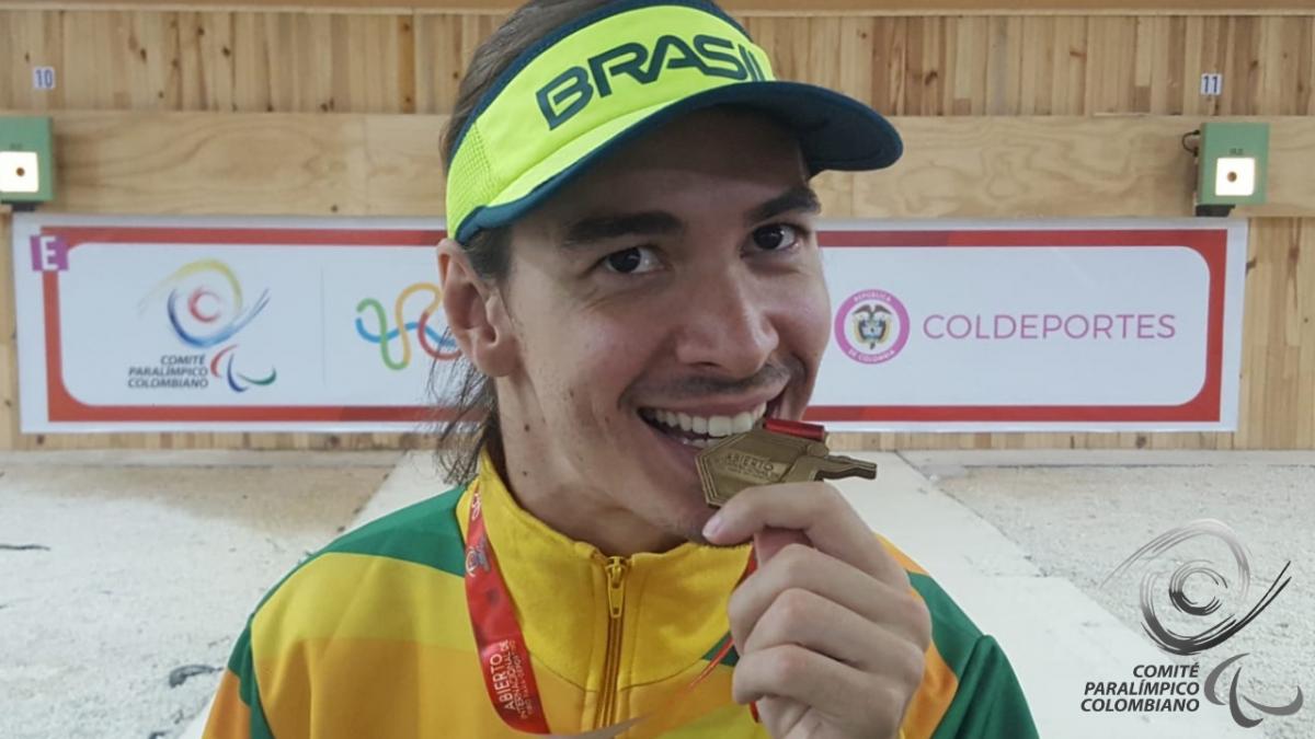 Brazilian male shooting Para sport athlete bites his gold medal