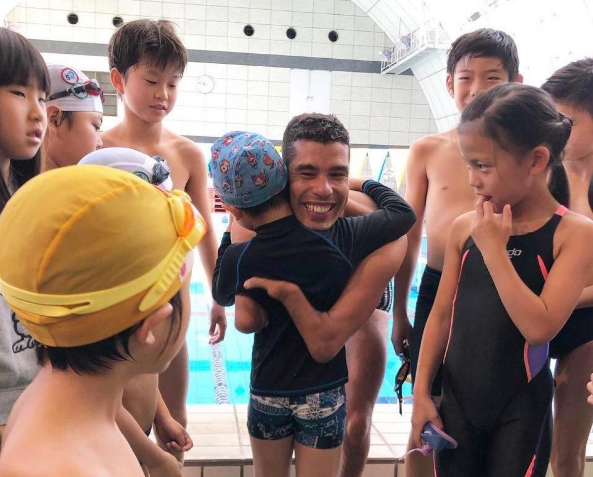 Daniel Dias - Tokyo A man hugging a child in the middle of a group of children