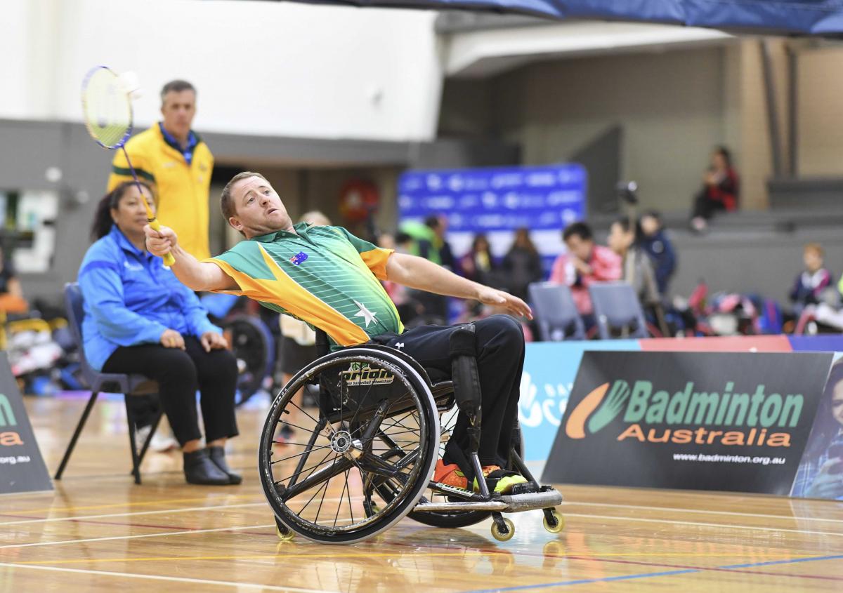 Male Australian badminton player in a wheelchair attempts to hit the birdie in the air