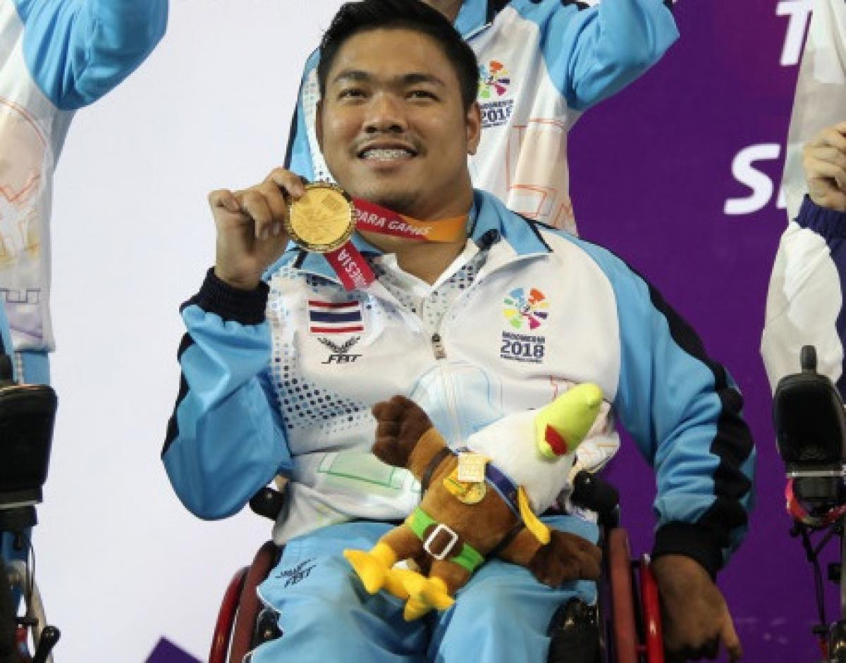 male boccia player Worawut Saengampa smiles and holds up his gold medal