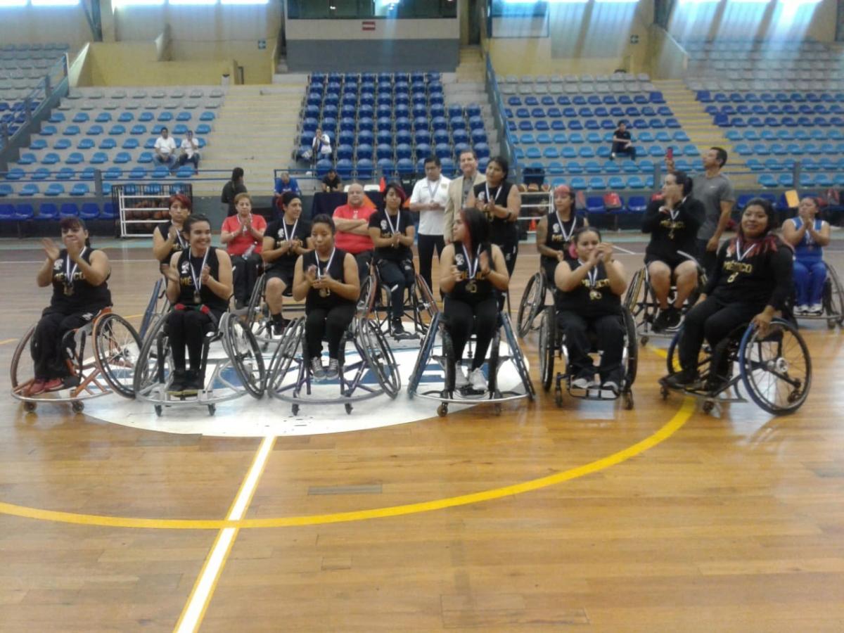 Female Mexican wheelchair basketball players pose after a victory