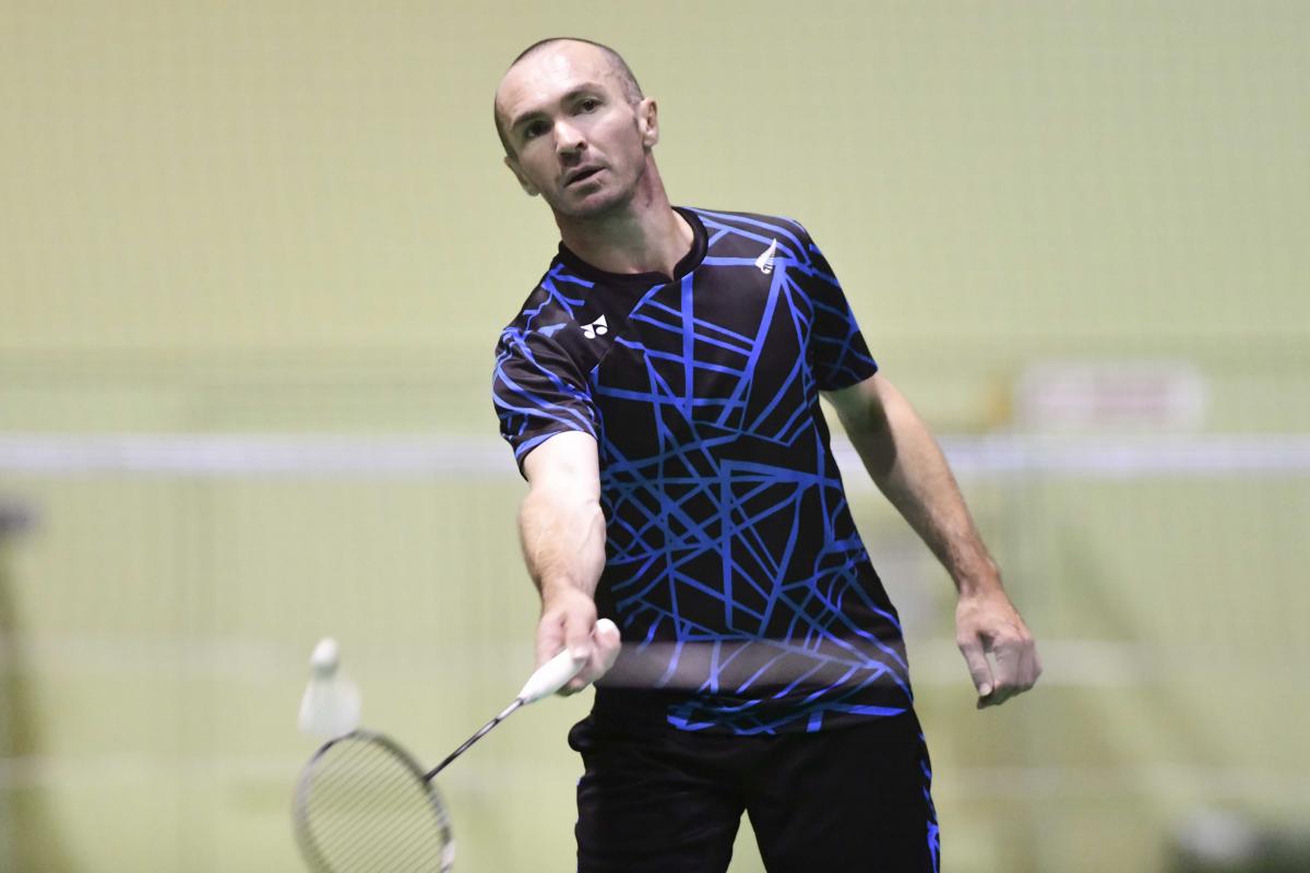male Para badminton player Corrie Keith Robinson standing and playing a forehand shot
