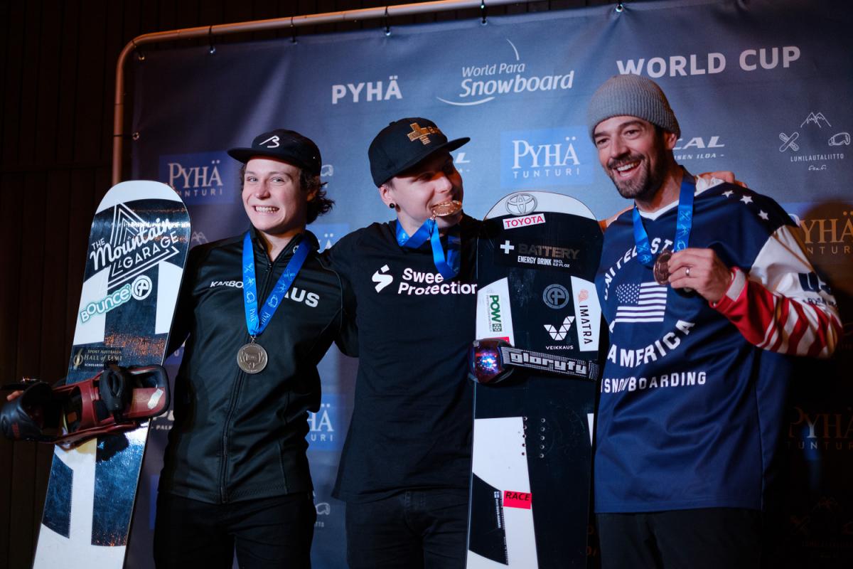 Three male snowboarders pose together with their medals