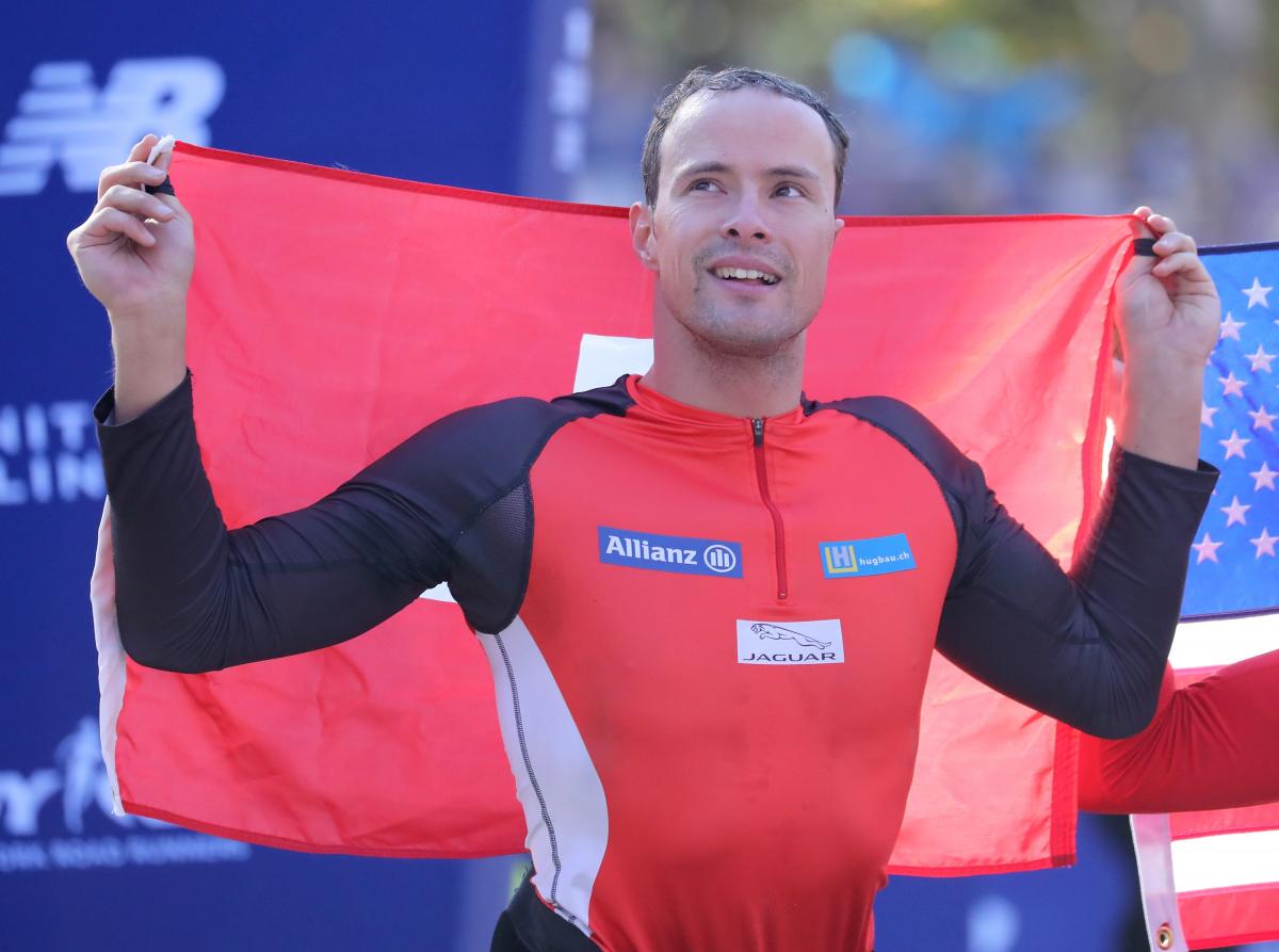 male wheelchair racer Marcel Hug holding up a Switzerland flag