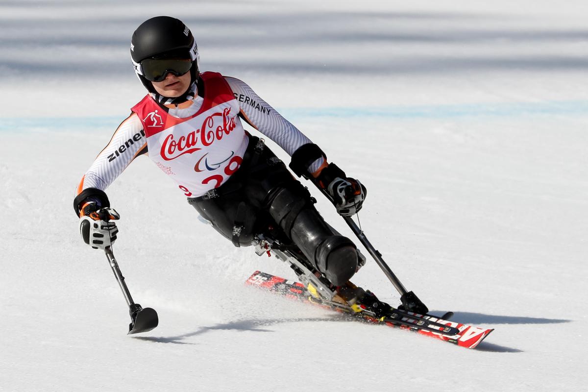 female Para alpine skier Anna-Lena Forster leans to the left as she skis down the slope