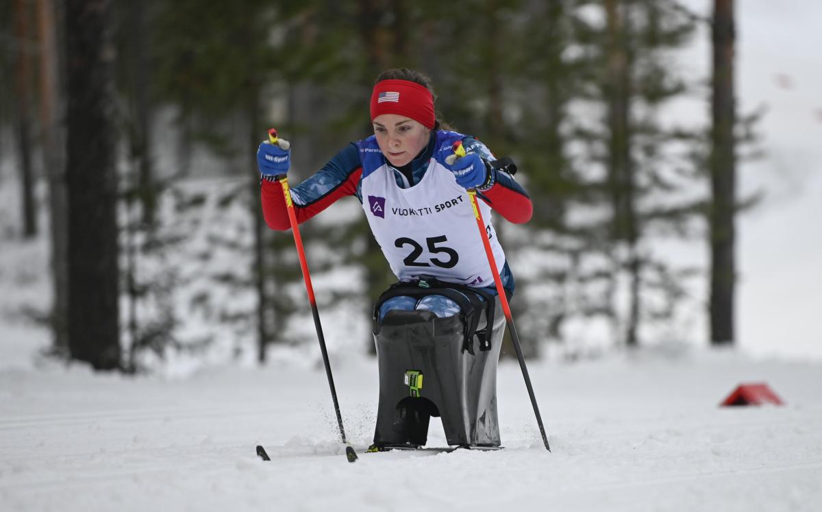 female Para Nordic sit skier Kendall Gretsch pushing through the snow