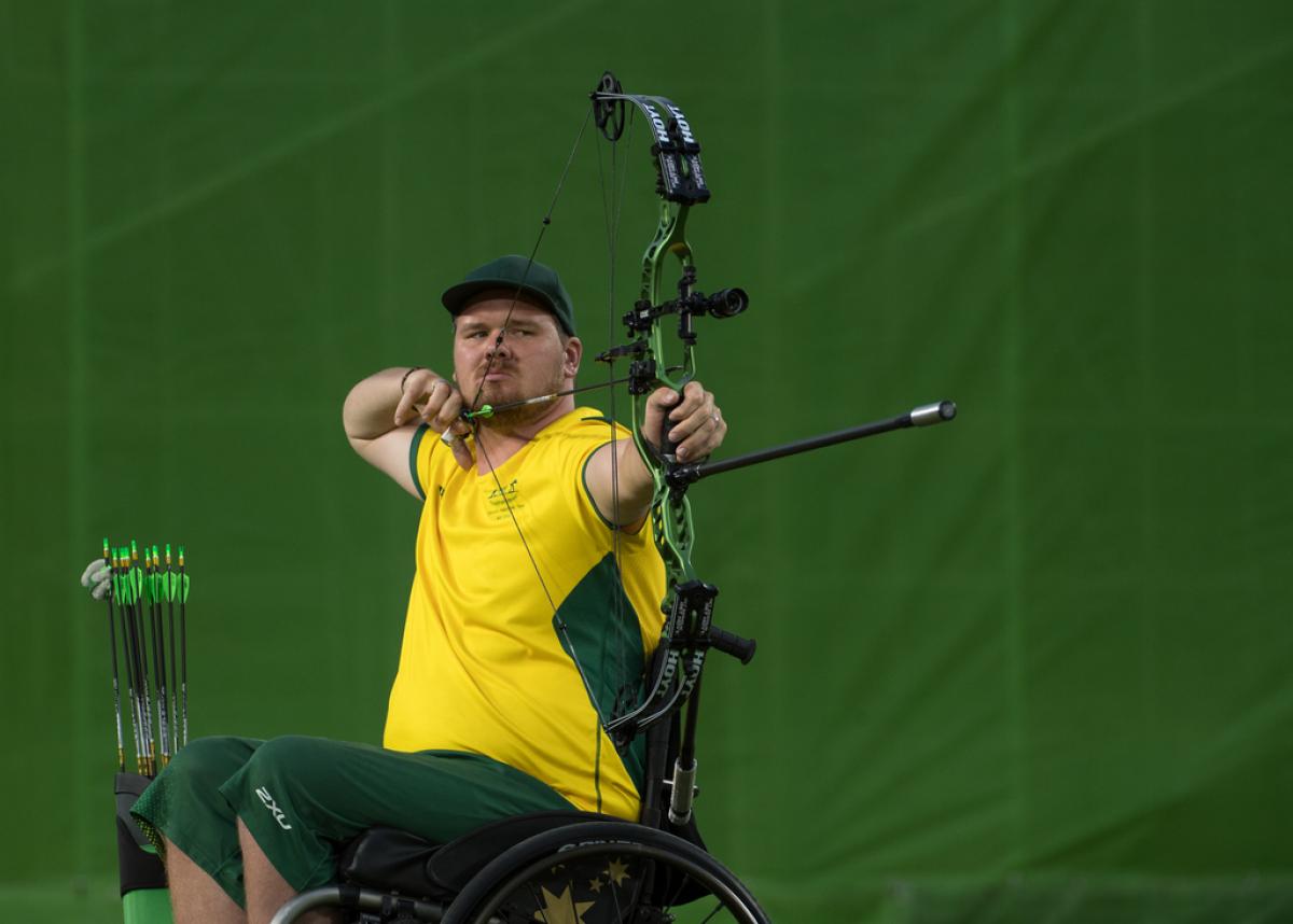 Australian male archer in wheelchair pulls back on his bow