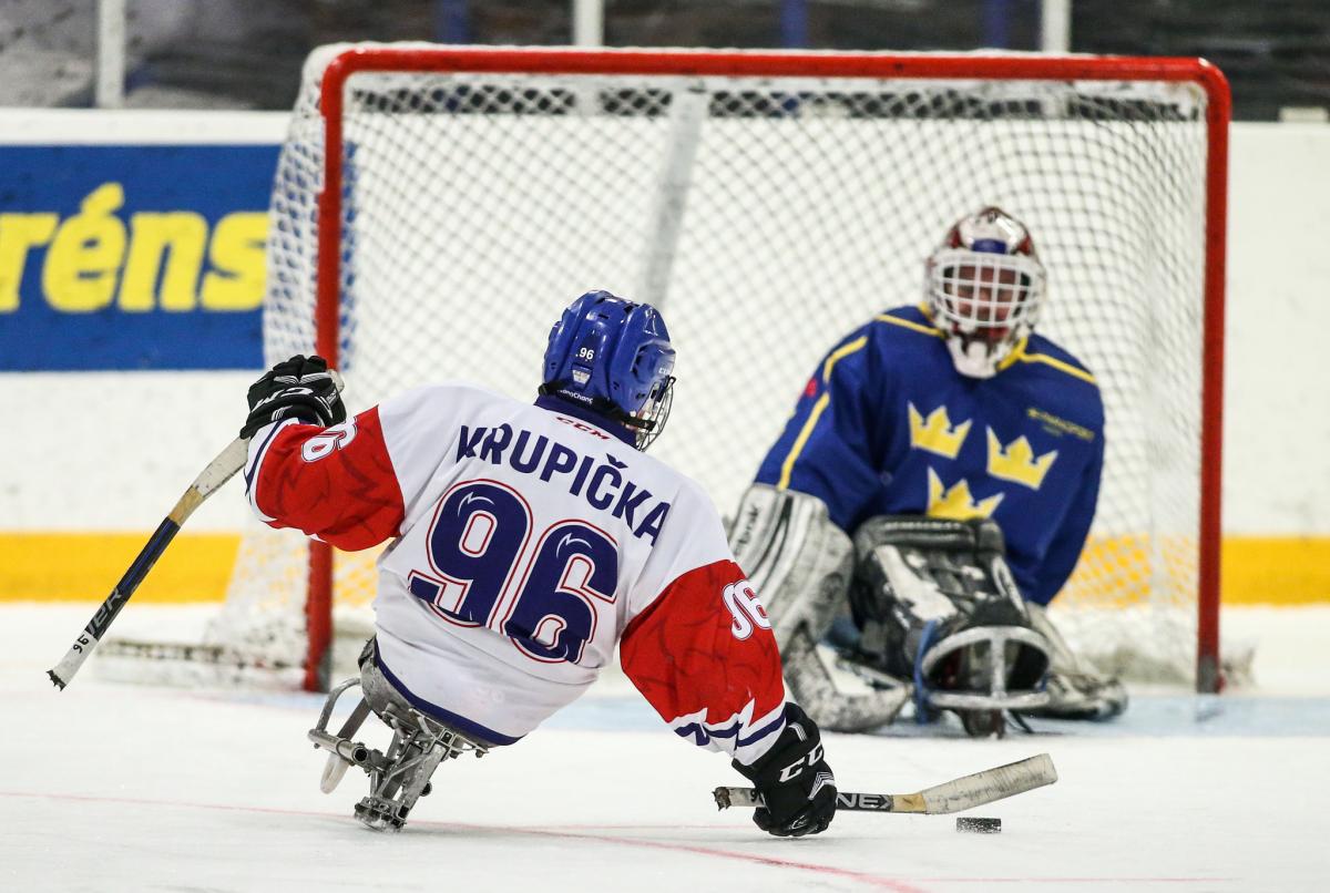 A Para ice hockey player taking a shot in front of the opponent's goal