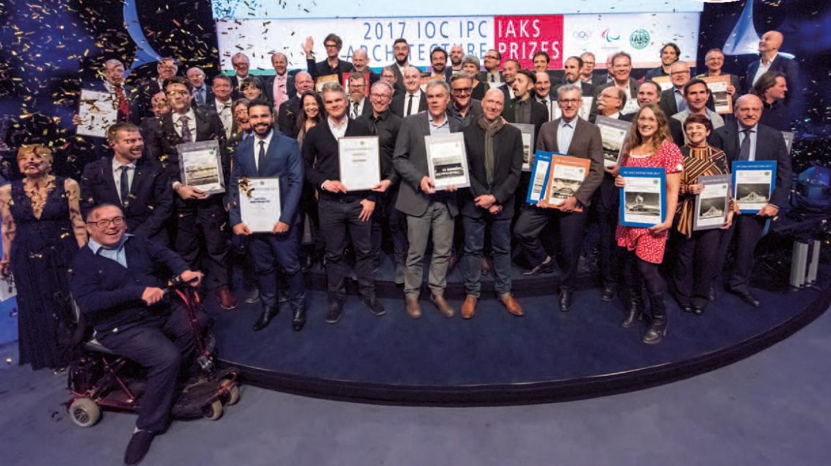 a group of male and female architects standing holding certificates and being sprayed with confetti