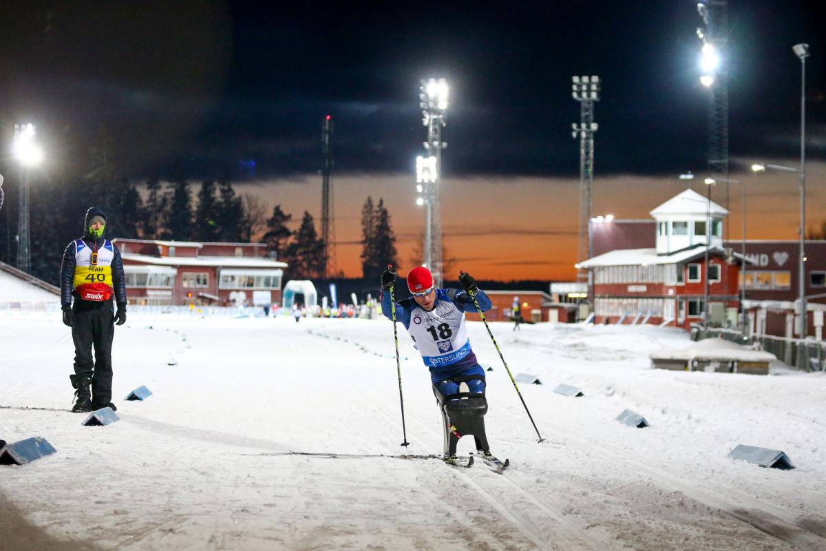 A man in a sitting ski competing in a biathlon race