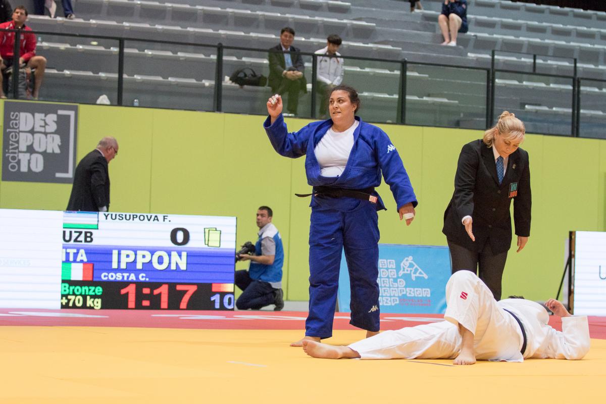 female judoka Carolina Costa stands over her opponent on the ground after winning the fight by ippon