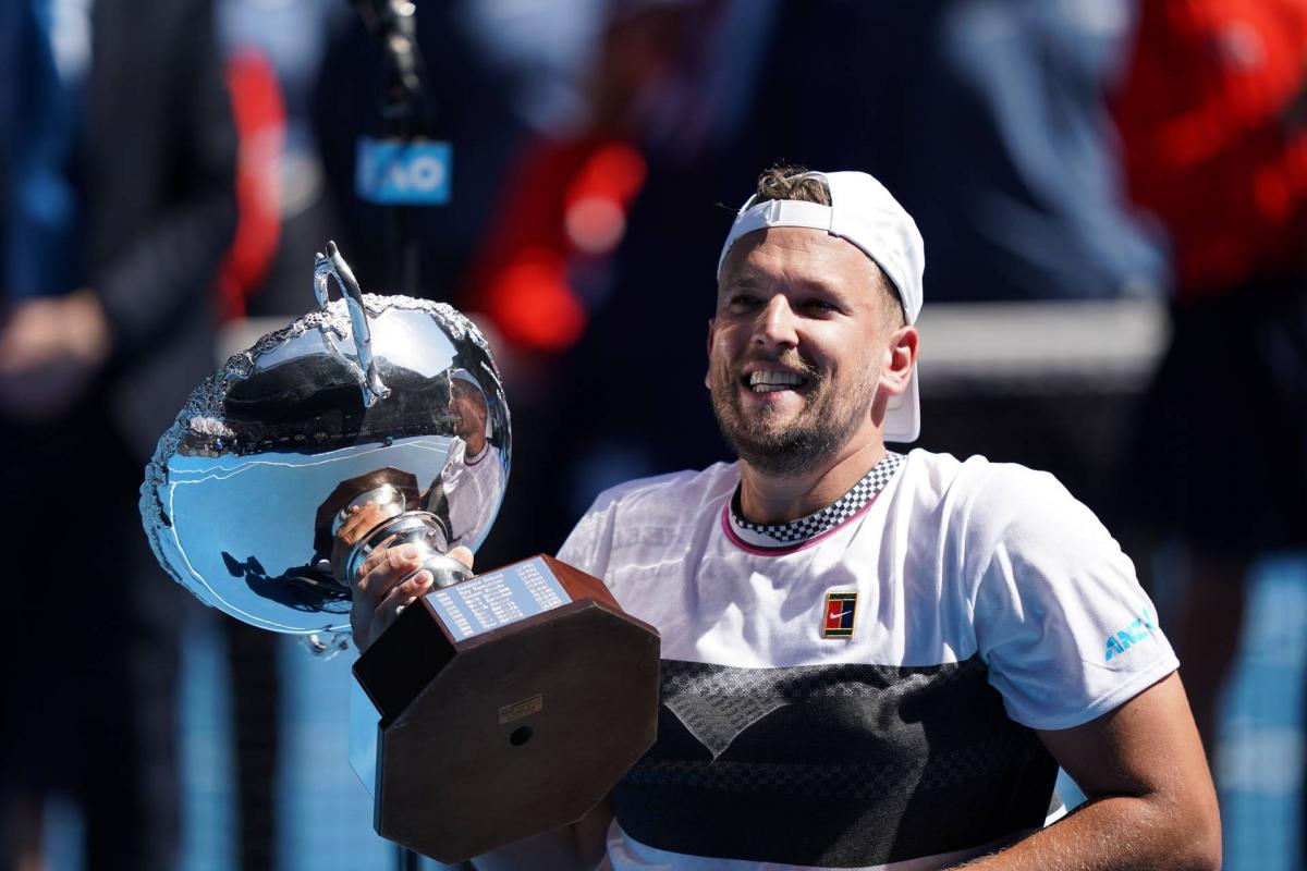 male wheelchair tennis player Dylan Alcott holds up a silver trophy and smiles