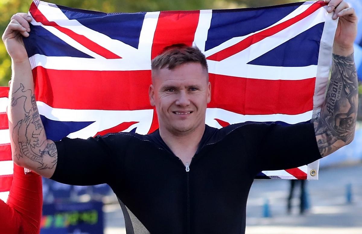 male marathon wheelchair racer David Weir holding up the British flag and smiling