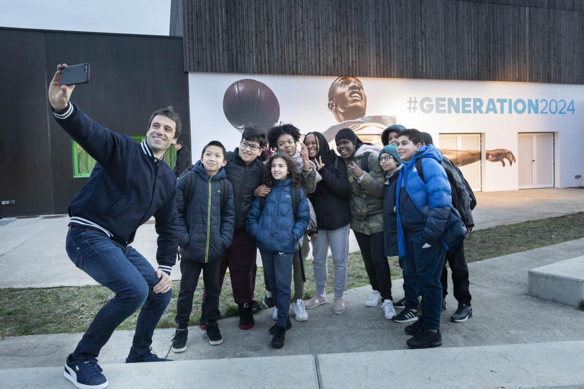 Tony Estanguet takes a selfie with some schoolchildren outside a school in Paris