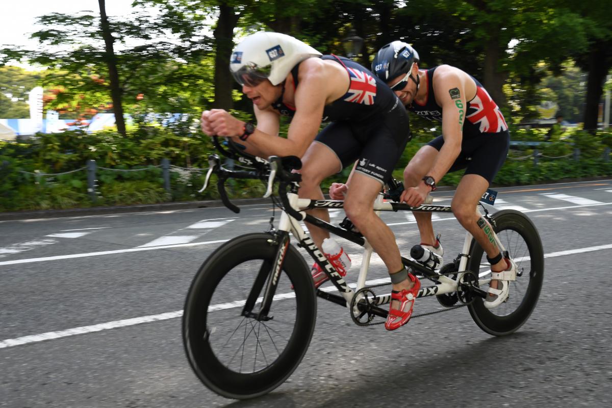 male Para triathlete Dave Ellis cycling on a tandem bike behind his guide