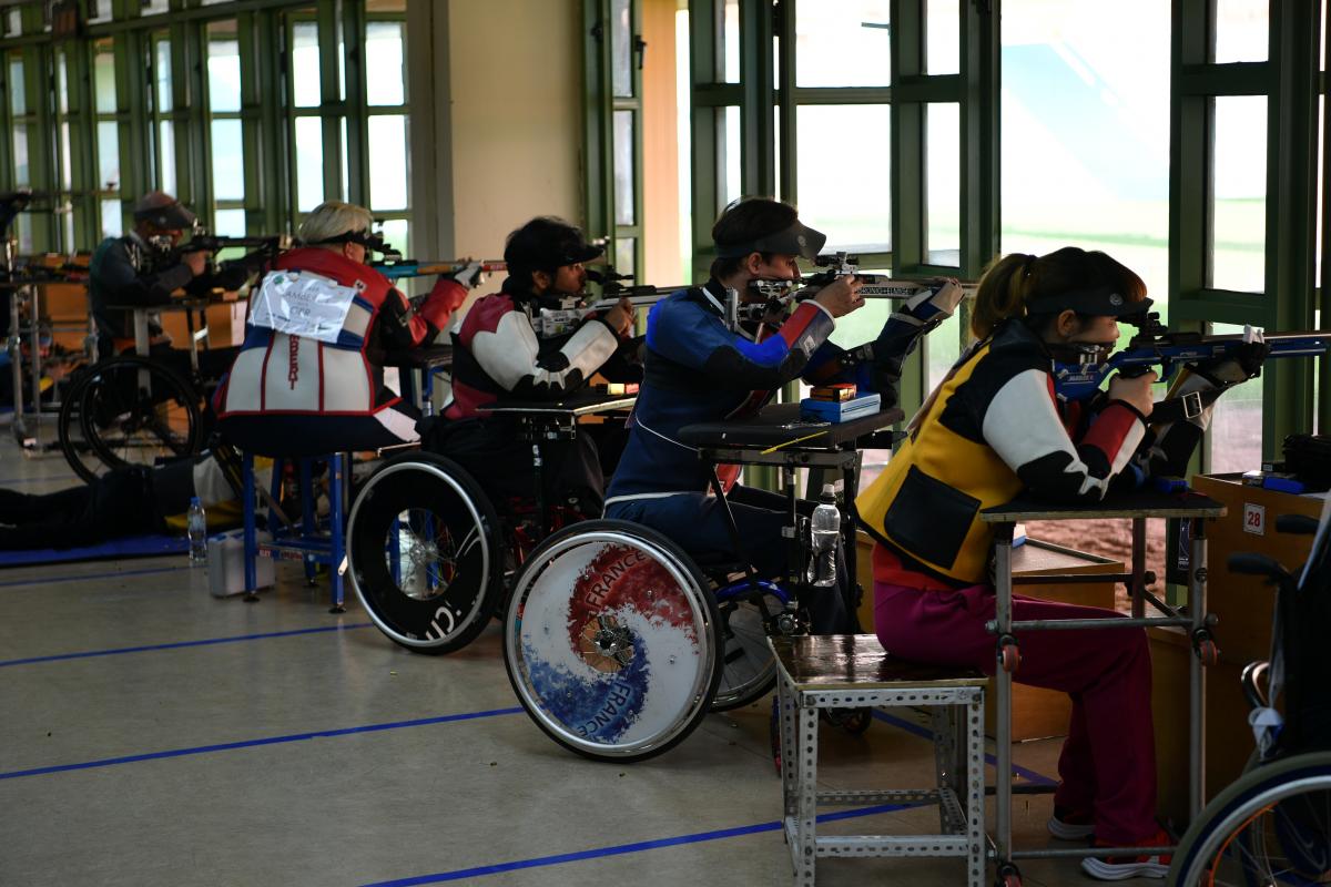 Para shooters sitting in wheelchairs firing rifles on the range