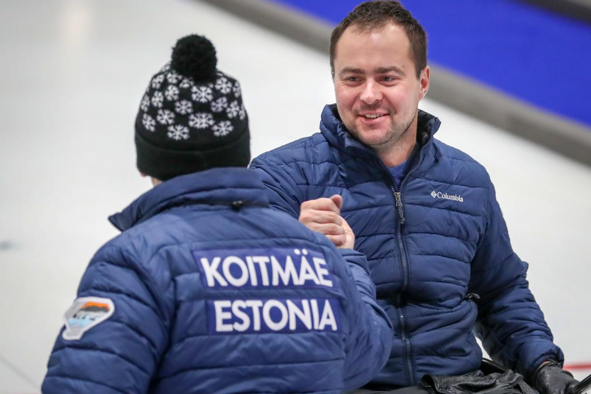 Two male wheelchair curling teammates clasp hands 