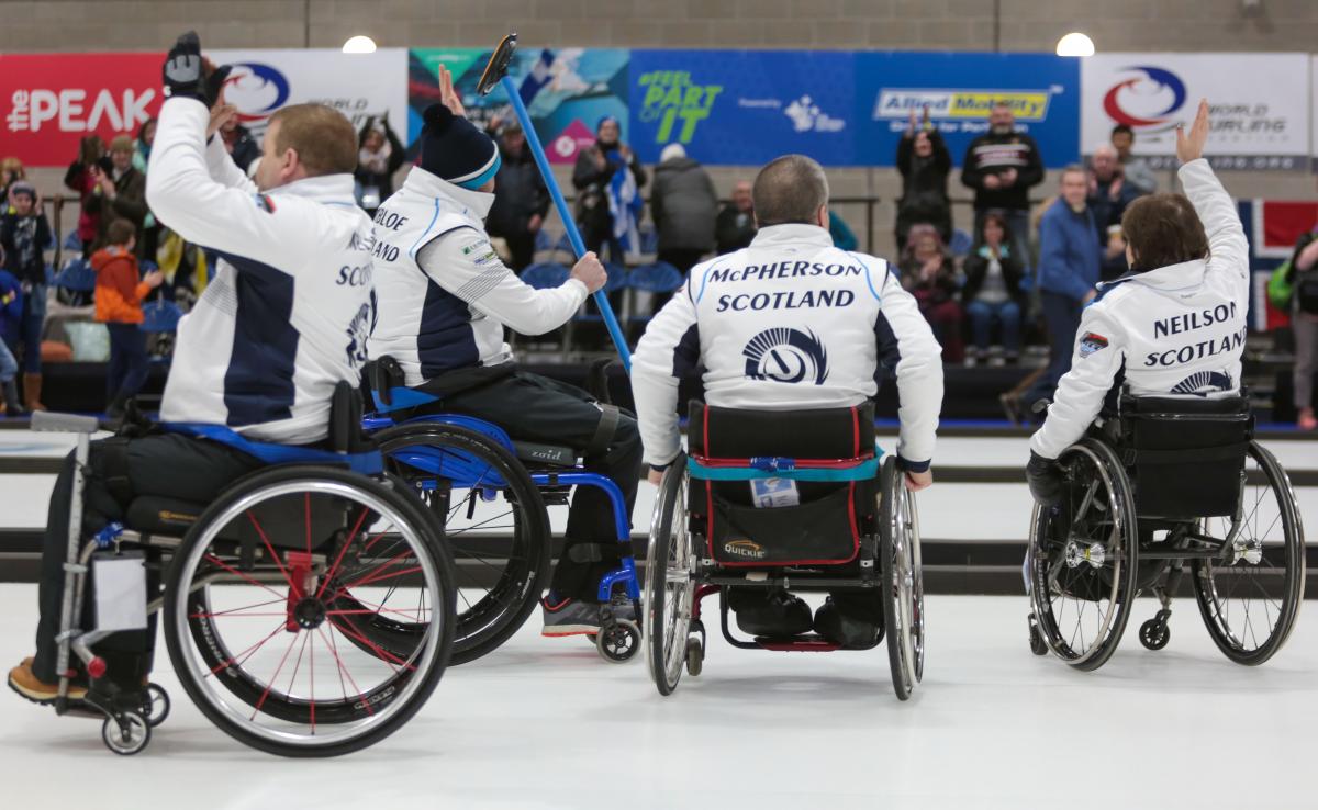 Scotland wheelchair curling national team - Stirling 2019 World Championships Four wheelchair curlers celebrating and waving to the crowd