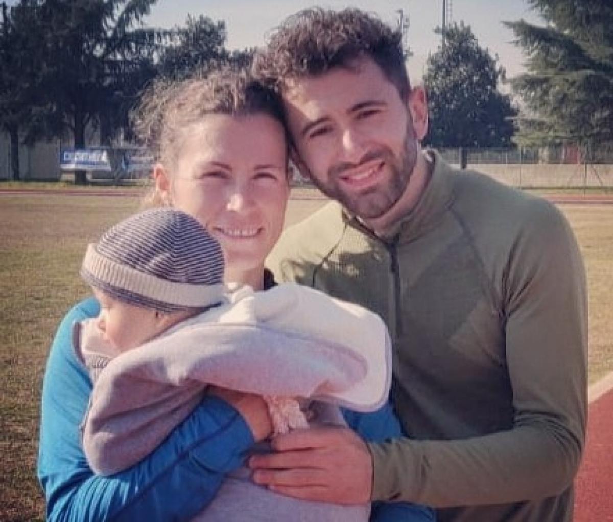 Female Para athlete Arjola Dedaj standing next to her male partner holding a baby boy