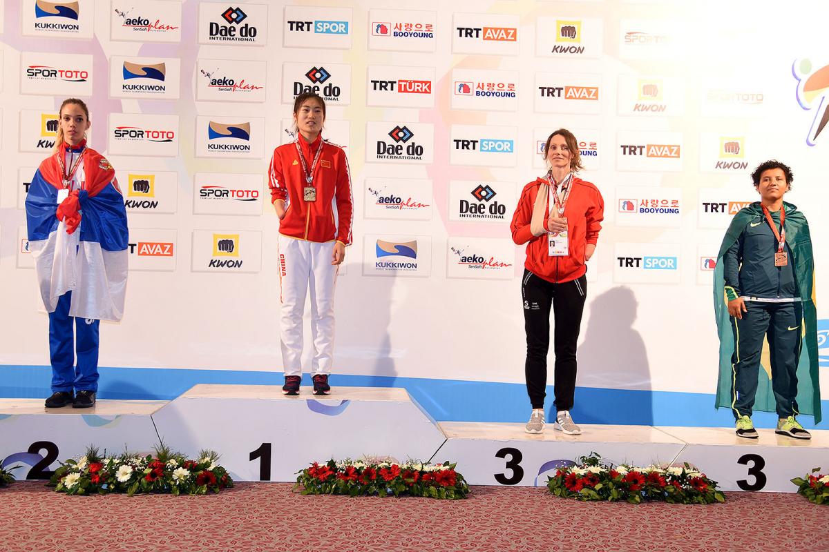 four female taekowondo fighters on the podium with Yujie Li on the top step