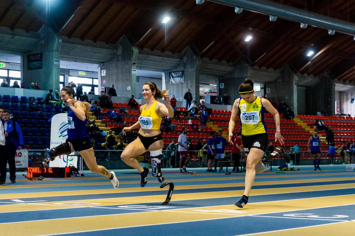 three female single amputee sprinters crossing the finish line