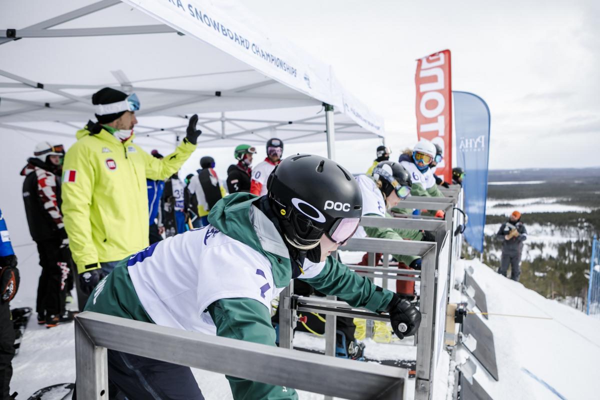 Female snowboarders line up at the start gate ready to go