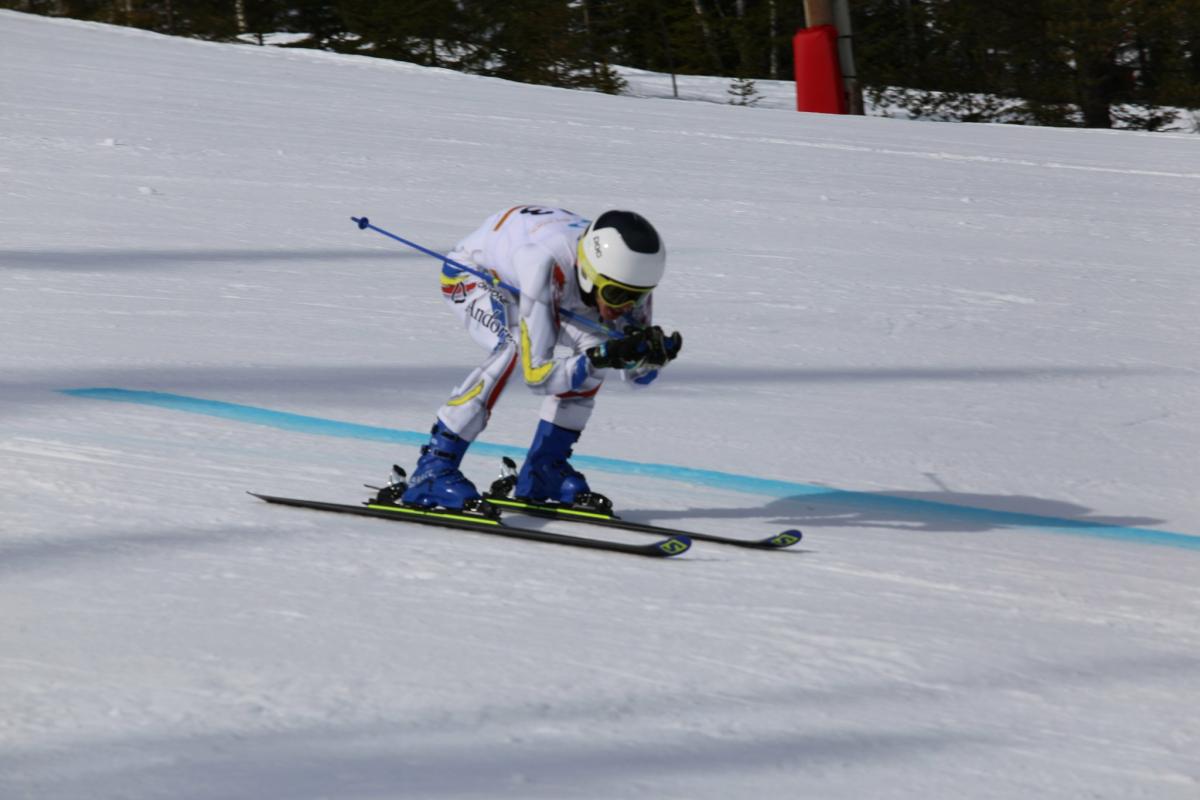 male Para alpine standing skier Roger Puig Davi crouches down as he crosses the finish line