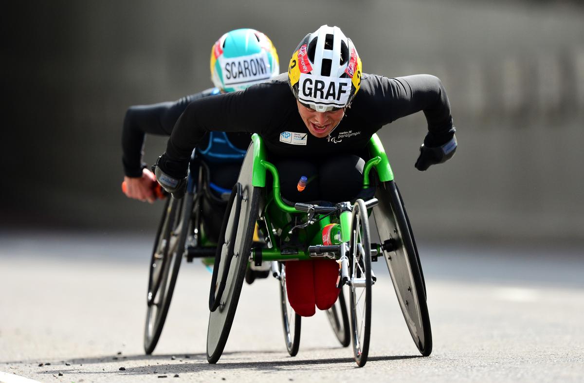 female wheelchair racer Sandra Graf leading another athlete duringa road race