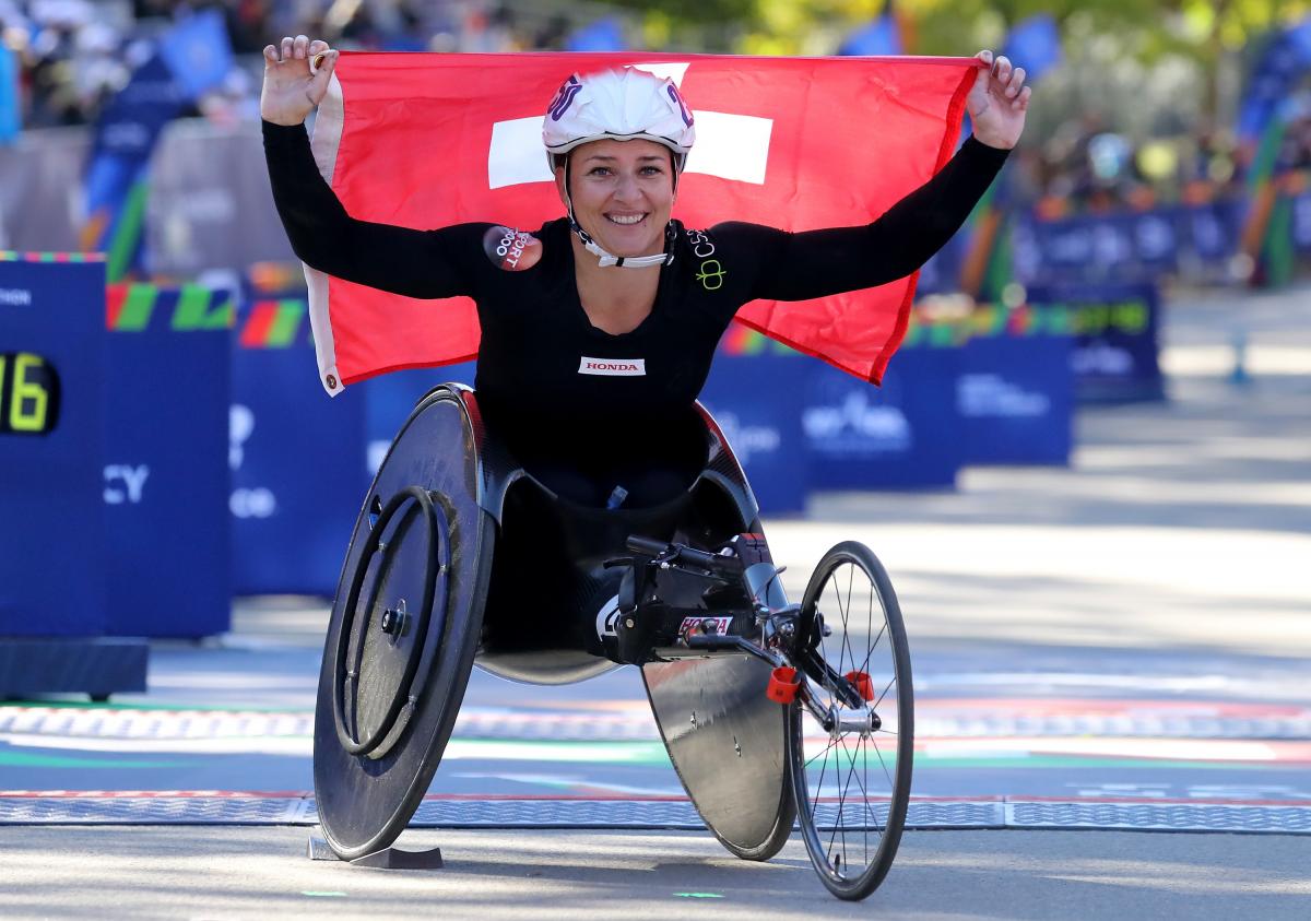 female wheelchair racer Manuela Schaer holding up a Swiss flag