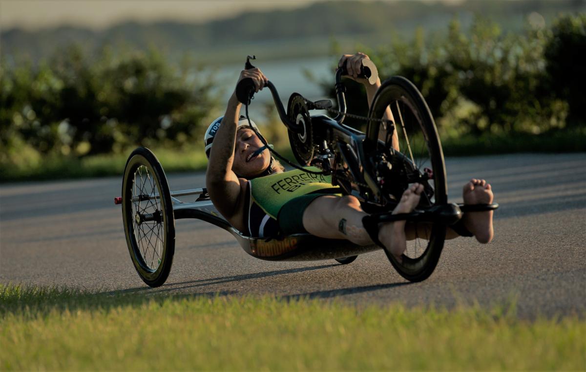 three female Para triathletes in wheelchairs on the podium holding flowers