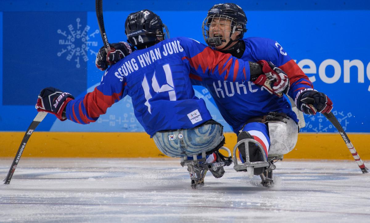 Two Para ice hockey players hug on the ice rink