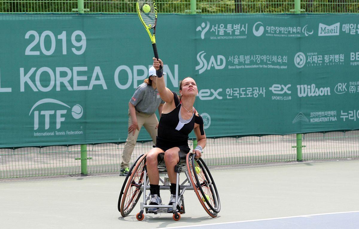 female wheelchair tennis player Marjolein Buis hits an overhead forehand on a hard court
