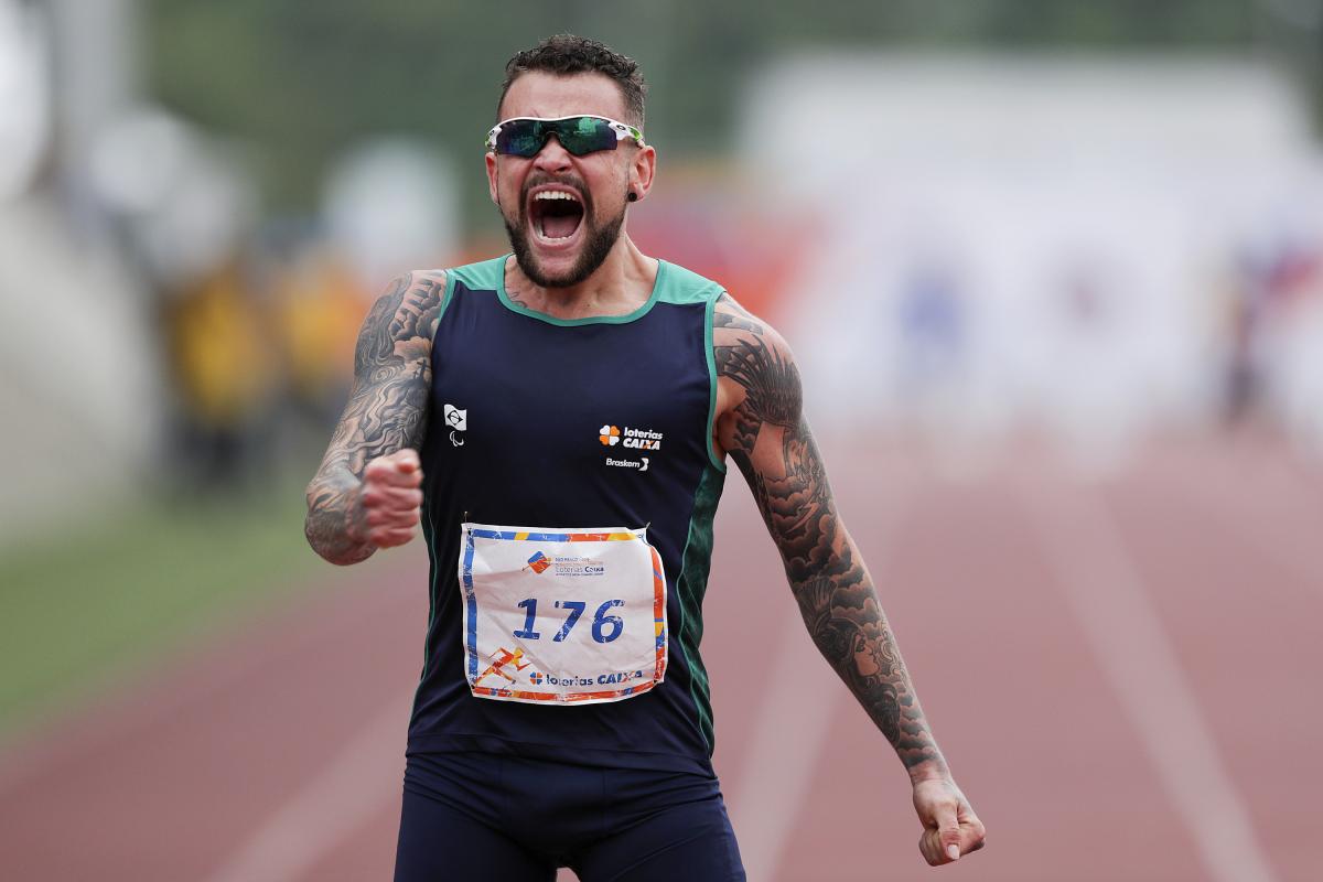 male Para athlete Vincent Rodrigues yells out as he crosses the finish line to win the race
