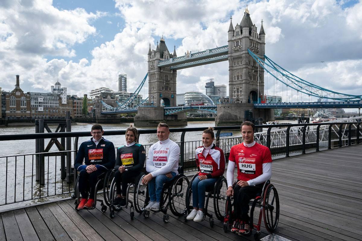 Five wheelchair athletes sitting in a row at the edge of the River Thames with London's Tower Bridge in the background