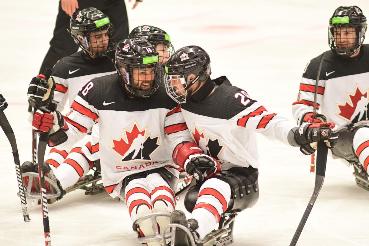 male Para ice hockey player Antoine Lehoux celebrates with another player hugging on the ice