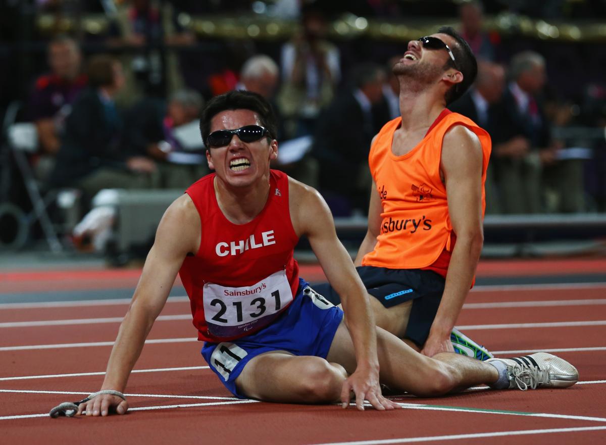 Chilean athlete and his guide on the floor exhausted after a race