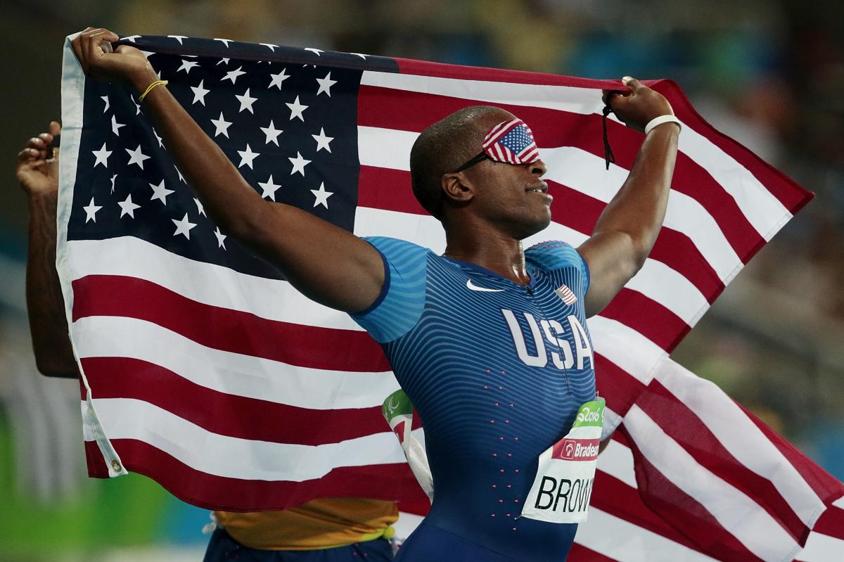 male vision impaired sprinter David Brown holding up the USA flag 