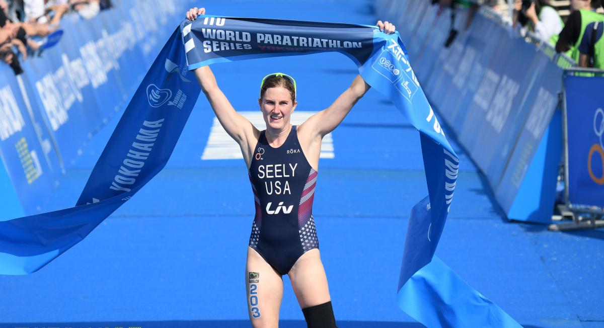 Female triathlete with left leg amputation celebrates as she crosses the finish line