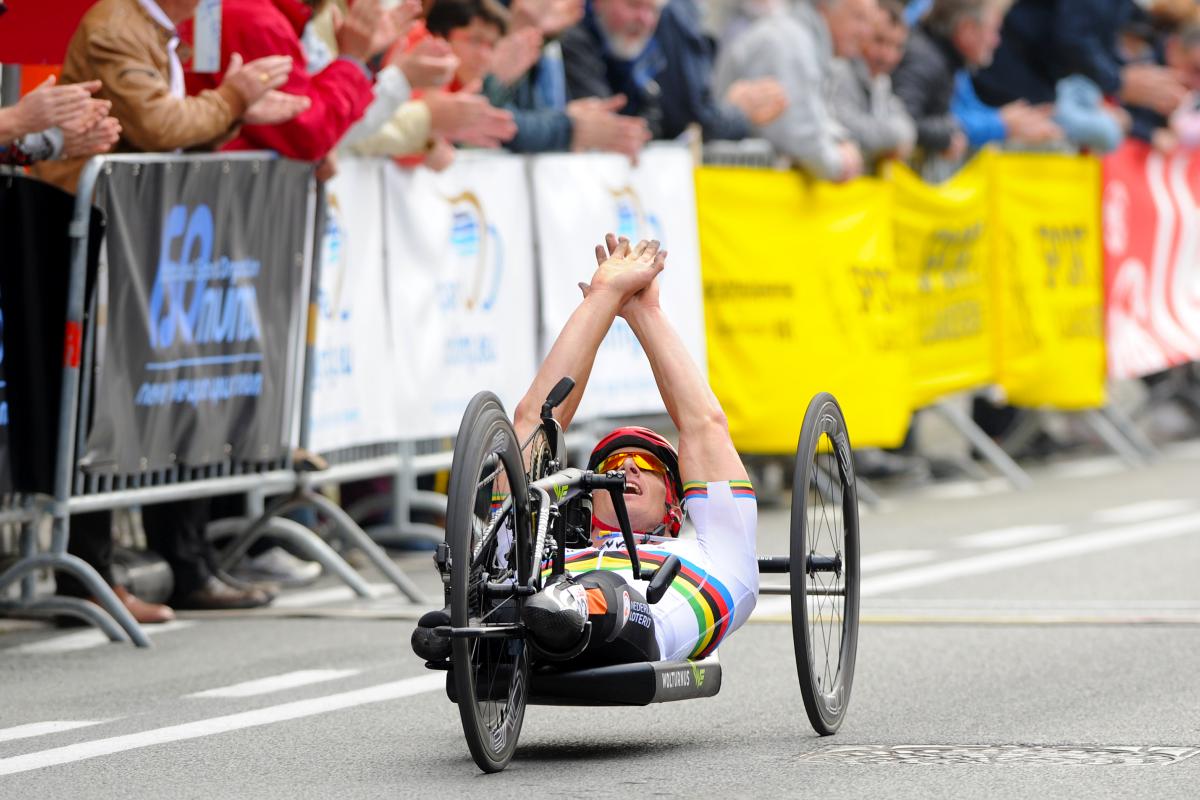 Dutch Para cyclist Jetze Plat celebrates with his hands up while crossing the finish line