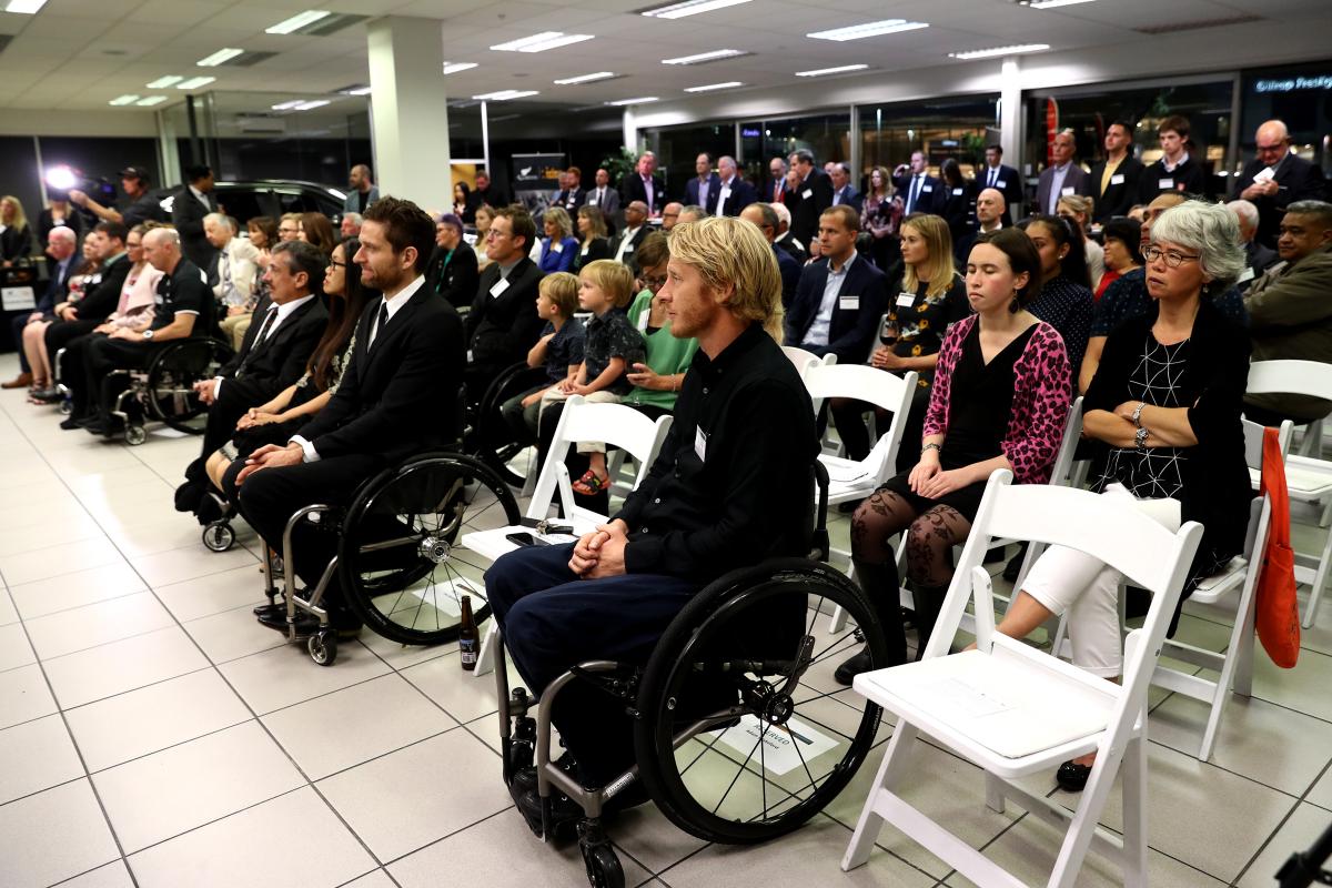 People gathered inside a room looking to the front and listening to a speaker